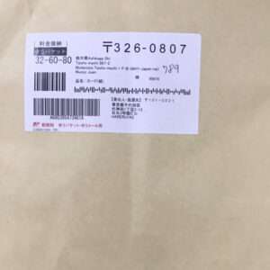 Brown envelope with a white shipping label showing Japanese text, barcodes, and tracking numbers at the top left corner.