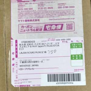 Close-up of a pink Japanese courier label on a cardboard box showing sender and recipient addresses, tracking barcode, and QR codes.