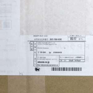 Delivery label on a cardboard box with Japanese text, barcode, and Amazon.co.jp address.