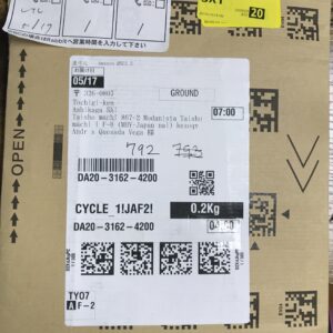 Brown cardboard parcel with multiple shipping labels, barcodes, and QR codes visible on the front surface.