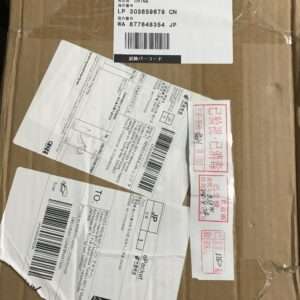 Brown cardboard parcel with a white shipping label containing Chinese/Japanese text and a barcode (barcodes visible).