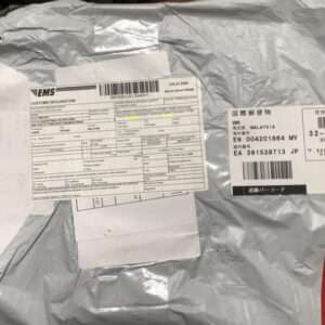 Grey padded parcel with EMS shipping labels, customs declarations, barcodes, and a red FRAGILE sticker.