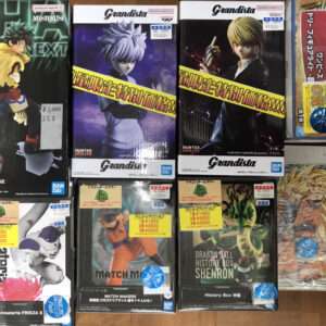 Assorted boxed anime action figures on a wooden floor, including Dragon Ball, Naruto, and Grandista lines.