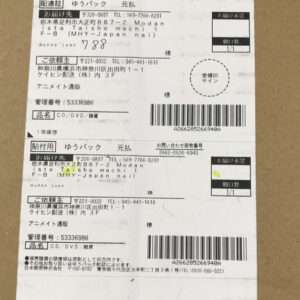 Shipping label on a brown cardboard box with barcodes, Japanese addresses, and a circular stamp.