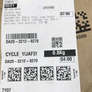 Shipping label on a cardboard package with barcodes, a QR code, weight 0.8 kg, and delivery times/dates visible.
