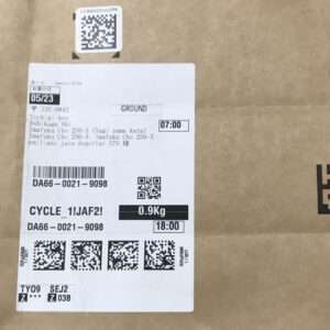 Cardboard box with a white shipping label featuring barcodes, QR codes, and a listed weight of 0.9 kg.