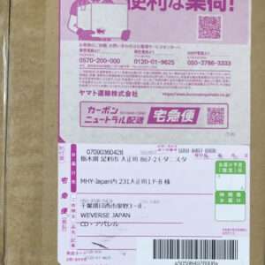 Pink Japanese courier label on a cardboard box, featuring a cartoon delivery person, QR codes, a barcode, and multiple address fields.