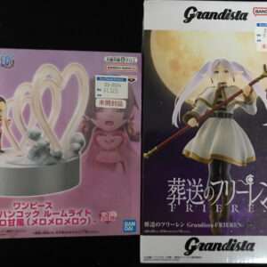 Two boxed anime figures displayed side by side: left is a pink One Piece set with heart-shaped rings; right is a Grandista Frieren figure with a staff against a moonlit backdrop.