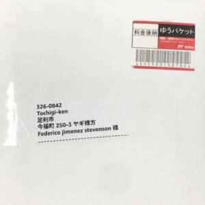 White envelope showing a Japanese mailing label with recipient address and a red postage sticker with barcode.