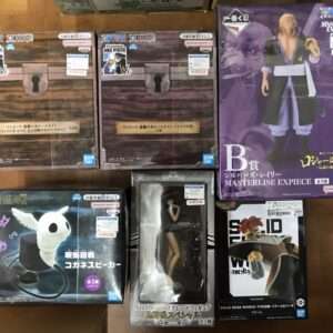 Row of Japanese anime figure boxes on a wooden floor, showcasing One Piece Masterlise and other character statues.