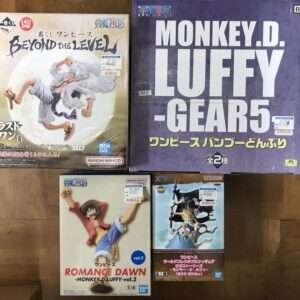 Boxed One Piece figure collection on a wooden floor, including 'Beyond the Level' Luffy and 'Gear 5' boxed set on top right.