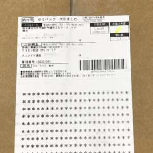 Japanese shipping label attached to a brown cardboard box, featuring a barcode, tracking/agent info, and a large block of asterisks (likely a receipt or packing slip).
