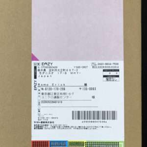 Cardboard box with a white shipping label containing a barcode, tracking numbers, and Japanese text.