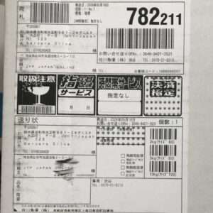 Japanese shipping label on a parcel with multiple barcodes, the tracking number 782211, service icons, and sender/recipient information.