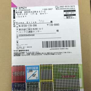 Shipping label on a package with Japanese text, sender and recipient addresses, barcode, and color-coded sections at the bottom.