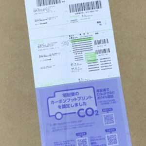 Cardboard box with white shipping labels on the top half and a purple CO2 information sticker at the bottom.