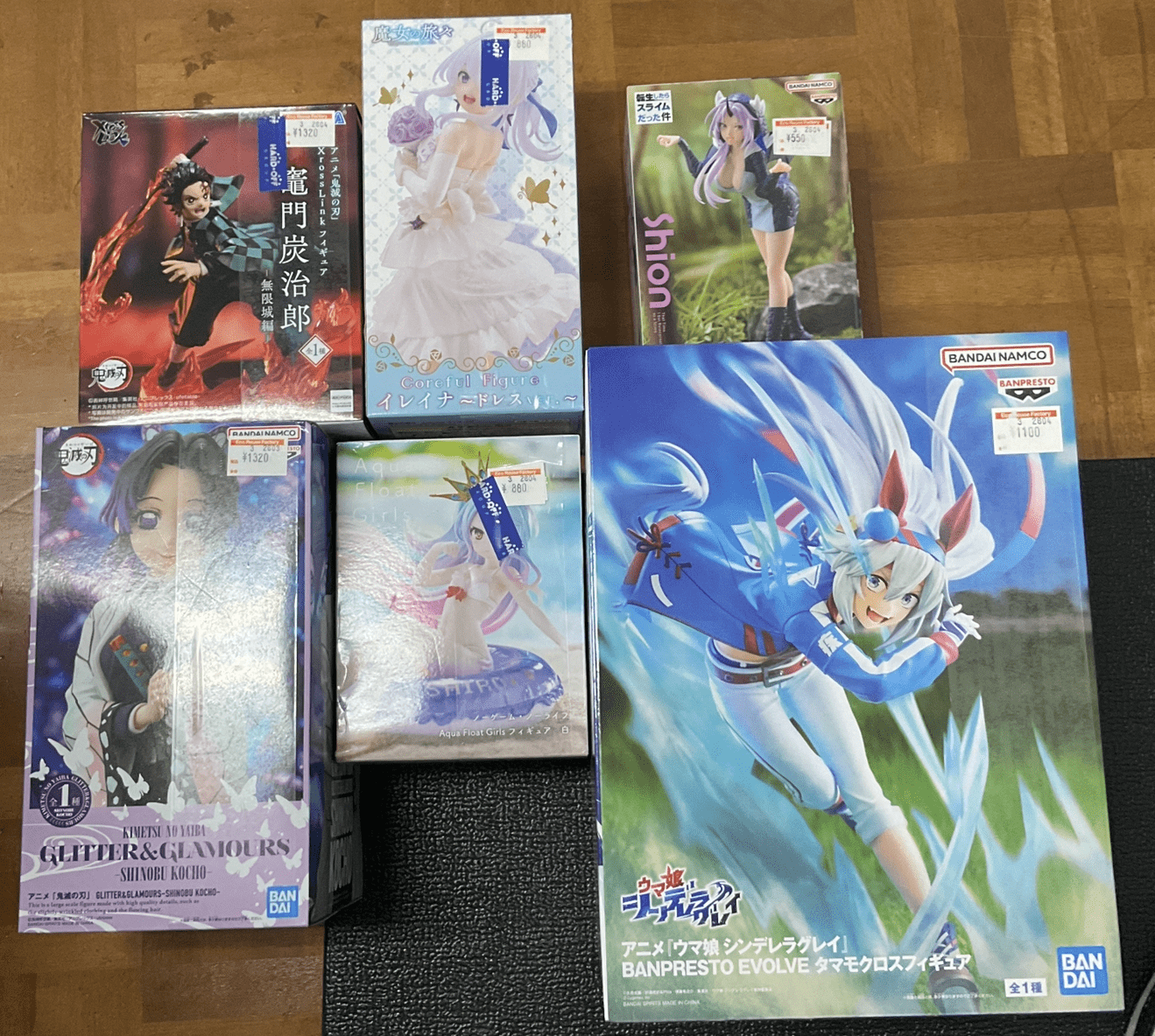 Ver Fotos Recientes 100 - Articulos Japan (post Box Japan) Collection of boxed anime figures displayed on a wooden floor, featuring multiple colorful boxes with character art and price stickers (Bandai Namco/Banpresto labels). Articulos Japan (Post Box Japan)