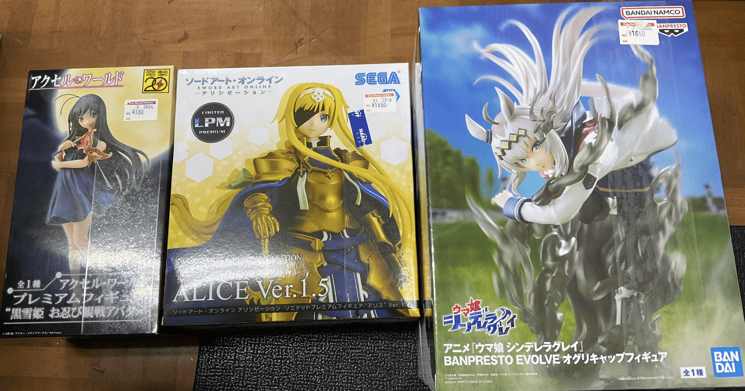 Ver Fotos Recientes 101 - Articulos Japan (post Box Japan) Three boxed anime figures on a wooden table: left a girl in a blue dress, center Sword Art Online ALICE Ver.1.5 figure, right a large Banpresto Evolve figure box with a silver-haired character Articulos Japan (Post Box Japan)