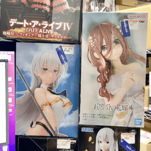 Shelf of boxed anime figures on a store display, including Fecha A Live IV, a red-haired figure, and a white-haired character among others with price tags visible.  Articulos Japan (Post Box Japan)
