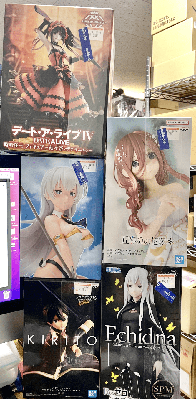 Ver Fotos Recientes 103 - Articulos Japan (post Box Japan) Shelf of boxed anime figures on a store display, including Fecha A Live IV, a red-haired figure, and a white-haired character among others with price tags visible. Articulos Japan (Post Box Japan)