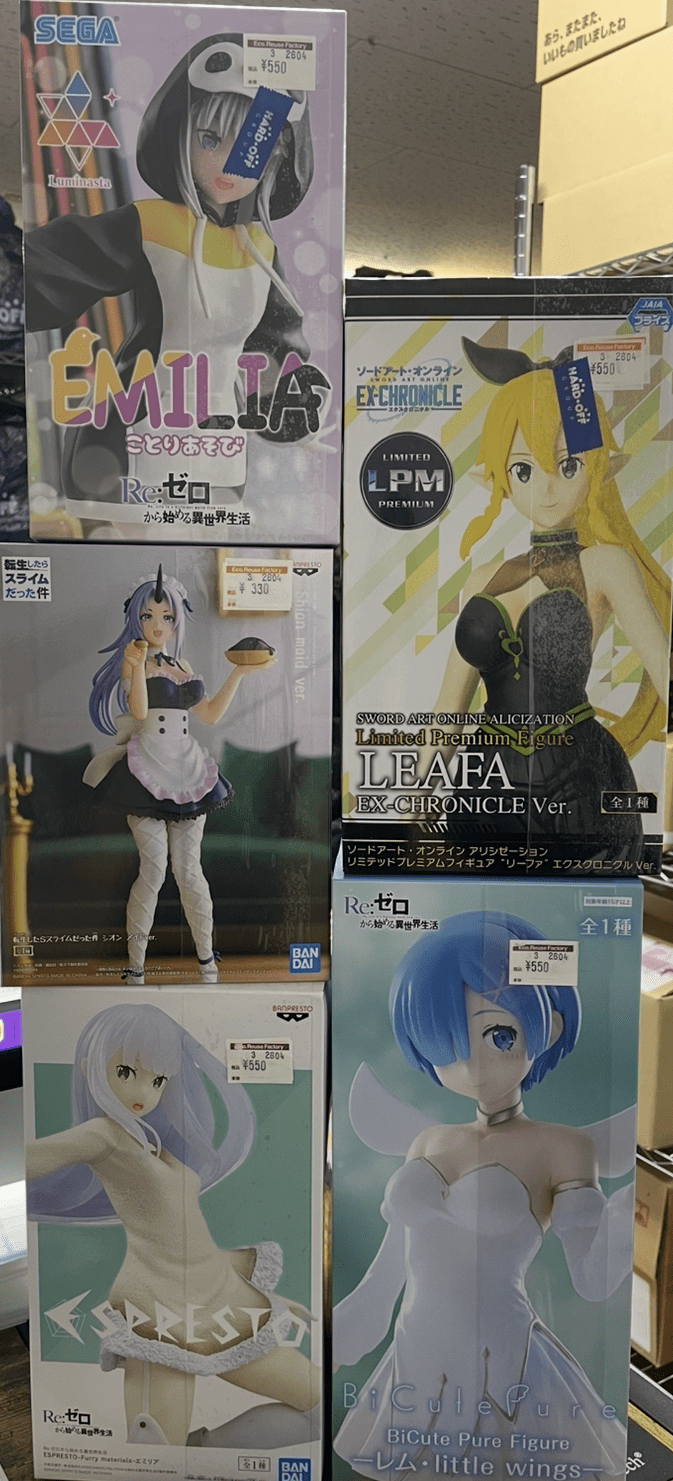 Ver Fotos Recientes 107 - Articulos Japan (post Box Japan) Stack of boxed anime figures on a display shelf, including Emilia from Re:Zero and Leafa from SAO EX-Chronicle (price tags visible). Articulos Japan (Post Box Japan)