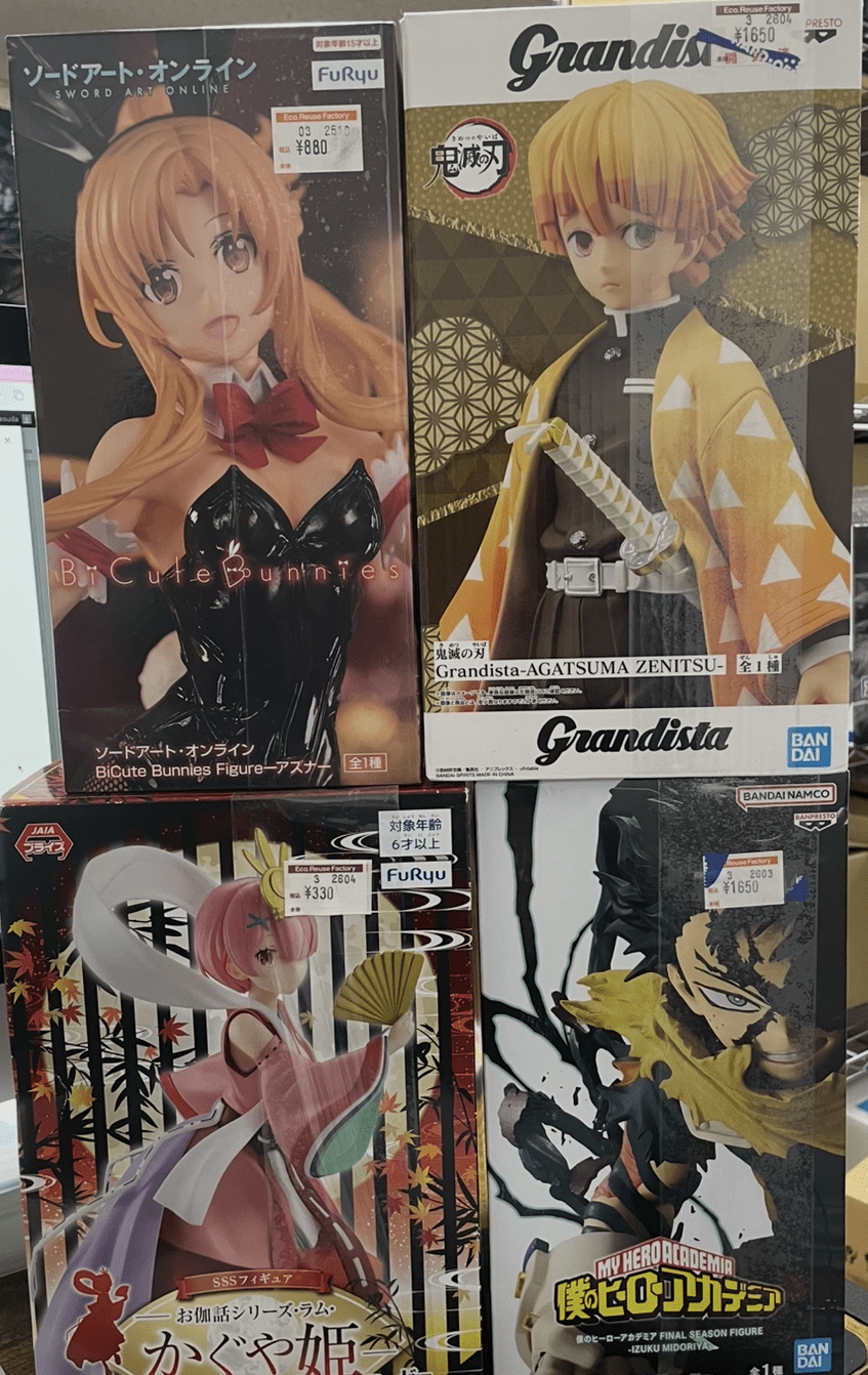 Ver Fotos Recientes 109 - Articulos Japan (post Box Japan) Shelf of boxed anime figures: left box features Asuna in a black bunny suit; right box shows Grandista Zenitsu with a yellow patterned cape; bottom left box has a pink-haired female figure in a pink outfit; bottom right box displays Izuku Midoriya from My Hero Academia in action pose. Articulos Japan (Post Box Japan)