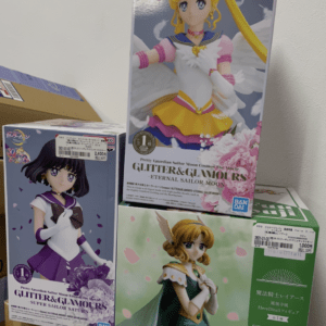 Stack of boxed anime figures on a shelf, including Sailor Moon glitter & glamour boxes and other characters.
