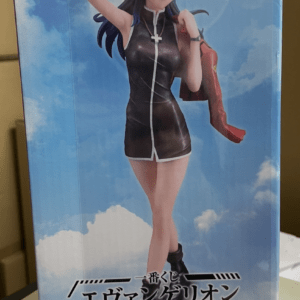 Boxed anime figure of a female character in a black sleeveless dress with white trim, blue hair, standing against a cloudy blue sky, holding a red jacket over one shoulder.