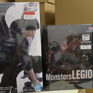 Two boxed anime figures on a shelf: left box shows a dark-haired character in a hoodie, right box features a red dragon-like creature from Monsters LEGION by Konami.