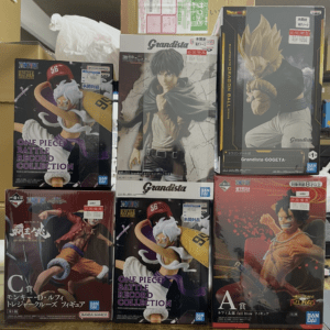 Assorted One Piece figure boxes on a shelf, including Grandista and Battle Record Collection lines with characters in dynamic poses.  Articulos Japan (Post Box Japan)