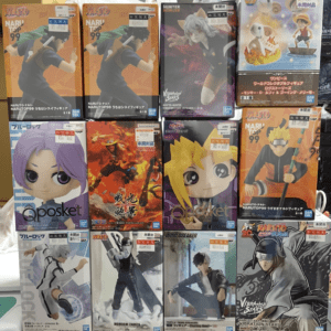 Row of collectible anime figure boxes on a store shelf, featuring Naruto and other characters like Qposket figures and Viviation Stars models.
