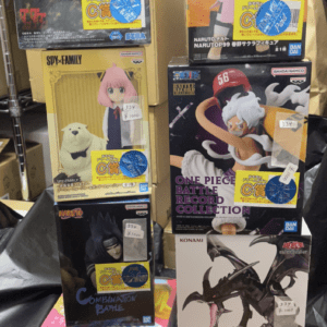 Stacked boxes of anime figure sets on a display shelf, featuring characters from Naruto, One Piece, Spy×Family, and more with price stickers visible.
