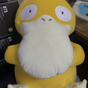 Soft yellow plush toy with oversized white beard and wide eyes on a desk fallaway pose.