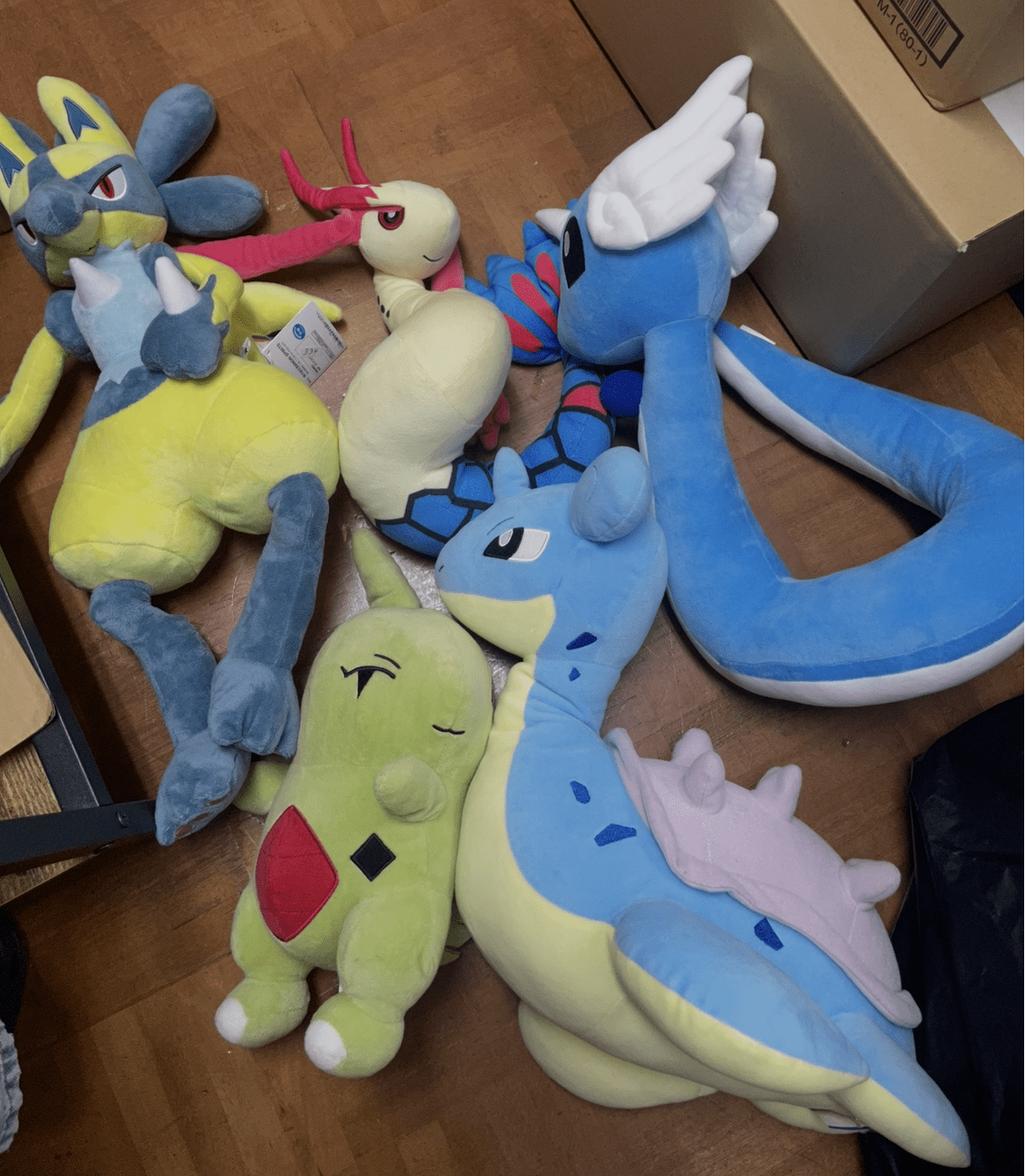 Ver Fotos Recientes 226 - Articulos Japan (post Box Japan) Pile of colorful plush toy dragons and creatures on a wooden floor, appearing soft and cuddly. Articulos Japan (Post Box Japan)