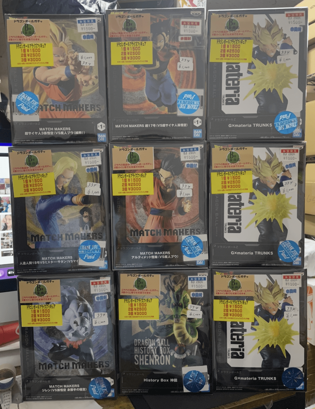 Ver Fotos Recientes 235 - Articulos Japan (post Box Japan) Grid of boxed Dragon Ball Match Makers figures on a store shelf, with price stickers visible on each box (Goku, Vegeta, Piccolo among characters). Articulos Japan (Post Box Japan)