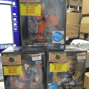 Stack of Dragon Ball Match Makers figure boxes on a store shelf; top box features Goku in orange gi with price stickers.