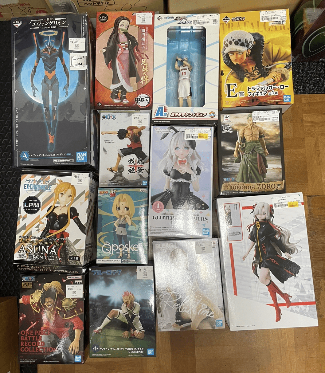 Ver Fotos Recientes 255 - Articulos Japan (post Box Japan) Assorted boxed anime figures laid out on the floor, including Evangelion, Demon Slayer, and One Piece boxes. Articulos Japan (Post Box Japan)