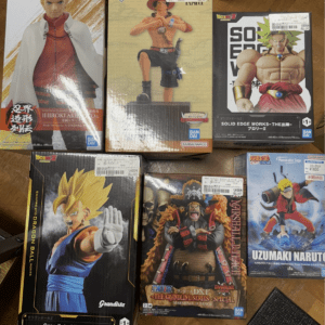 Six boxed anime figures on a wooden floor (Naruto, One Piece, Dragon Ball Z) showing characters in dynamic poses . . .