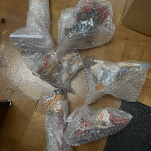 Several bubble-wrapped packages lying on a wooden floor, contents not visible.