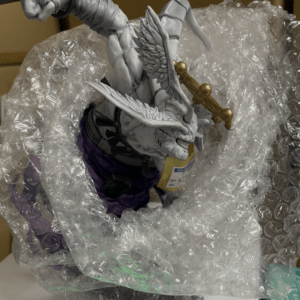 Gray dragon statue with wings and a gold crown, wrapped in bubble wrap for protection during transport.