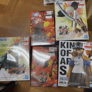 Collection of One Piece character figurine boxes on a wooden floor, featuring colorful artwork and Bandai branding.