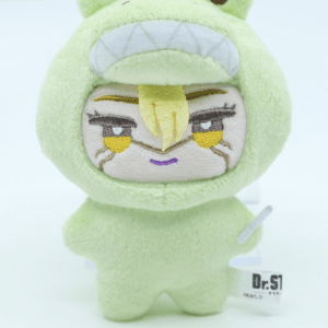 Green frog-themed plush toy with a hood, yellow embroidered face and a small smile, standing upright on a white surface.