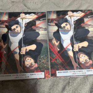 Two manga covers showing a dark-haired man hanging from a rope over a city at sunset, with red diagonal lines across the scene.