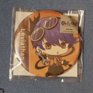 Round orange pin featuring a chibi character with purple hair and goggles, holding a chained weapon; 'Leviathan' text visible along the side in a plastic package.
