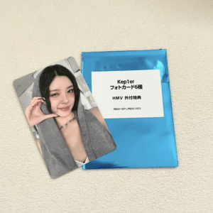 Blue gift envelope with a white label in Japanese text and a glossy photo card of a smiling woman on a beige surface.