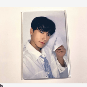 Portrait of a young man in a white shirt, holding a folded piece of paper.