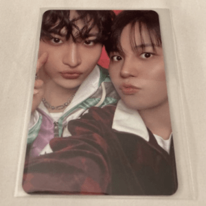 Two young men posing for a close-up selfie, lips pursed, in a printed photo on a beige surface.