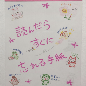 Poster featuring cute drawings and pink Japanese text: "読んだら すぐに 忘れる 手紙" (A letter you forget immediately after reading) on a light background.