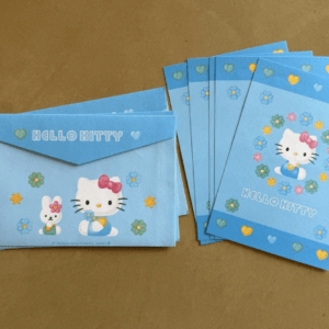 Stack of blue Hello Kitty gift envelopes/cards arranged on a brown surface with floral accents.
