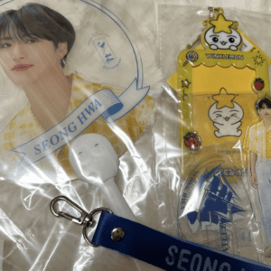 K-pop fan merch bundle: Seonghwa portrait, a white handheld fan, a blue lanyard with SEONG HWA, and yellow Winklemon display items.